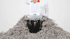 man in white shirt shredding financial documents
