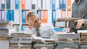 business man looking at piles and piles of documents