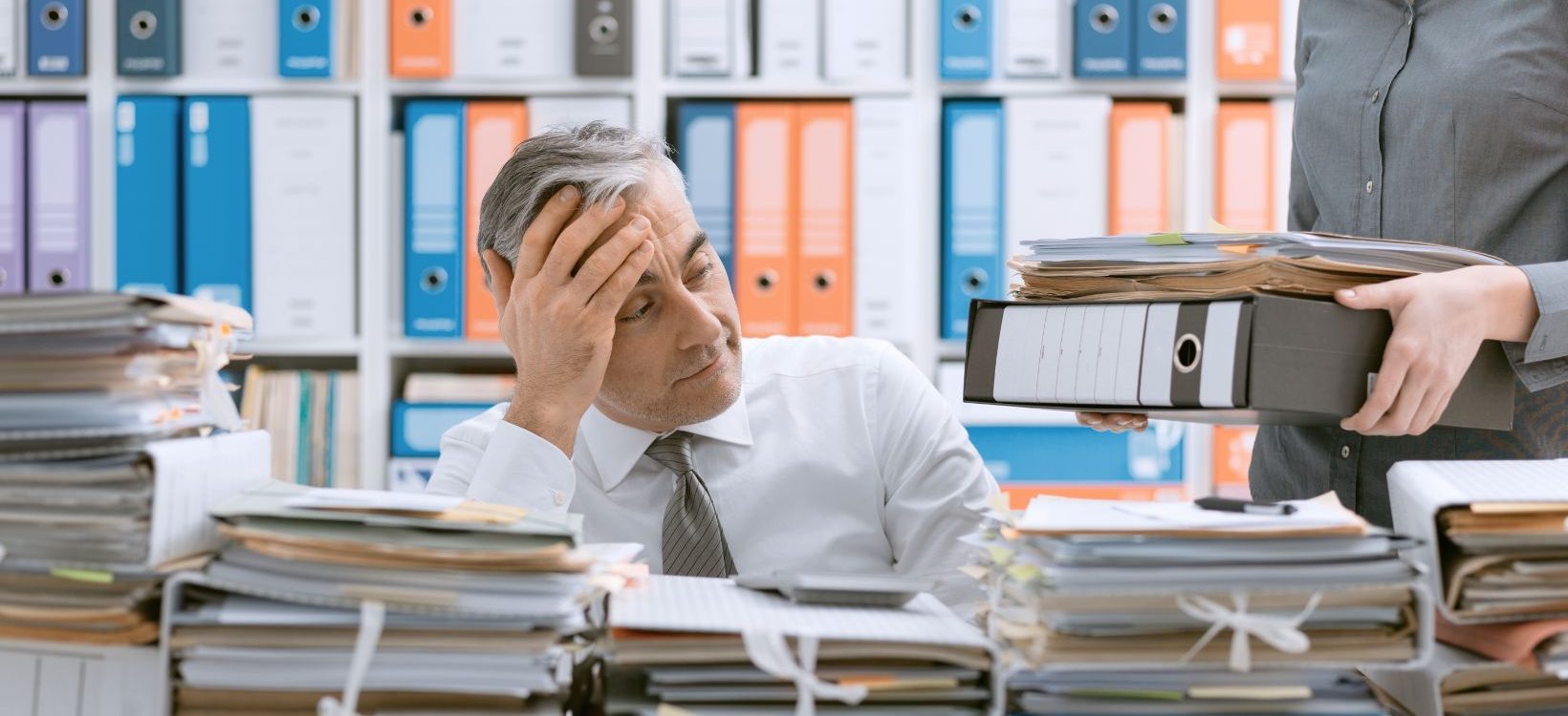 business man looking at piles and piles of documents
