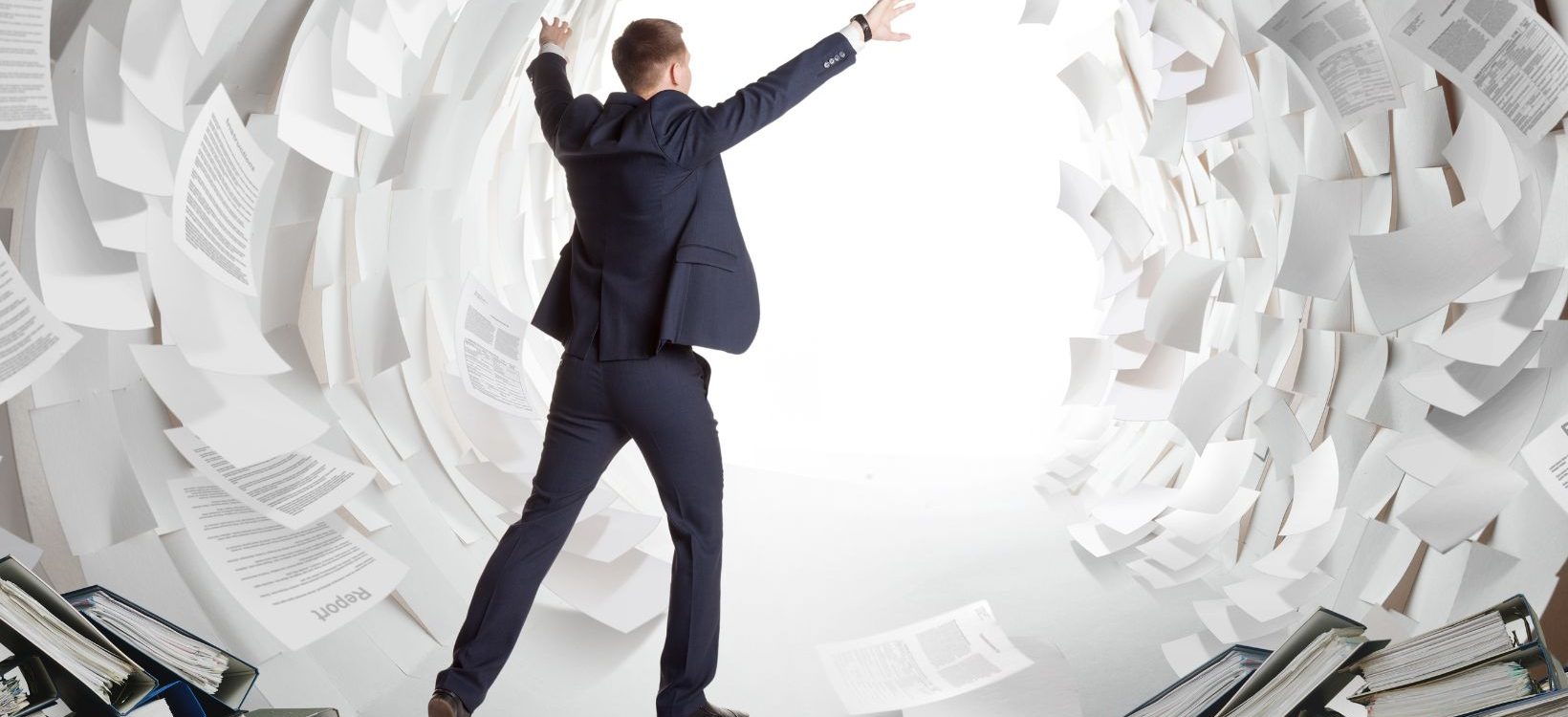 Businessman with documents flying all around him